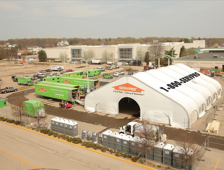 SERVPRO of Ascension Parish sets up a large tent from which it operates a fleet of green trucks and trailers.
